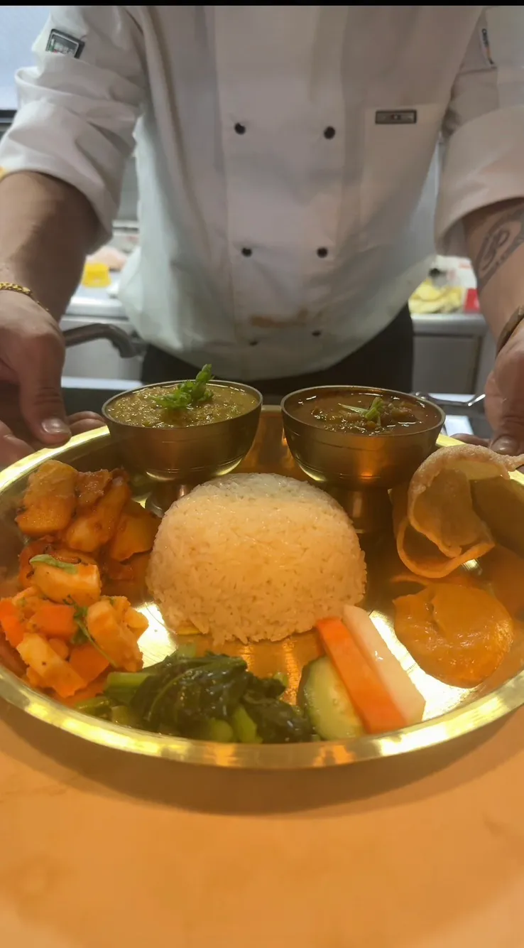 料理を仕上げるシェフとネパールタリ